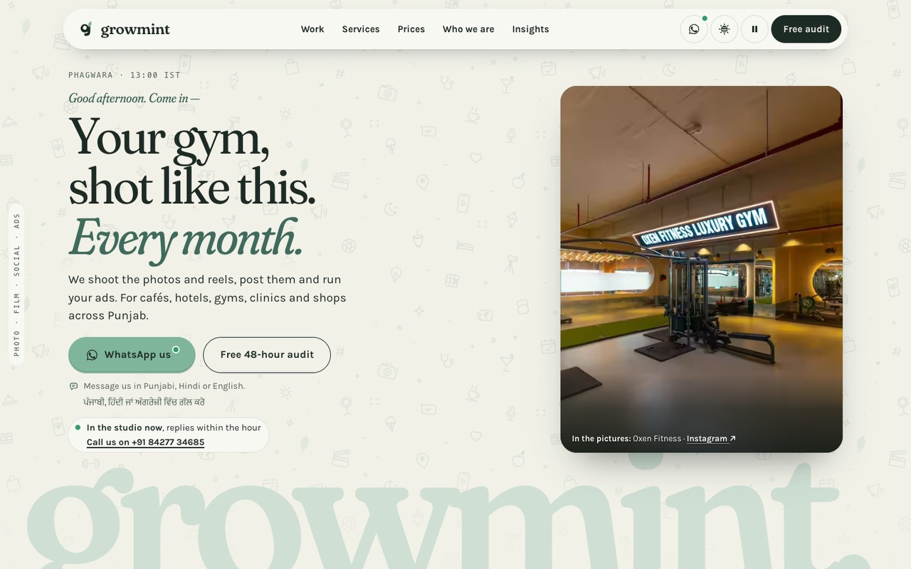 The studio’s home page on a laptop: ‘Your gym, shot like this. Every month.’, WhatsApp us and the free audit, and beside them the gym floor at Oxen Fitness under its lit sign, credited to Oxen Fitness.